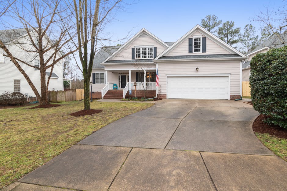 A well-maintained suburban house exterior with a large driveway, perfect for real estate listings.